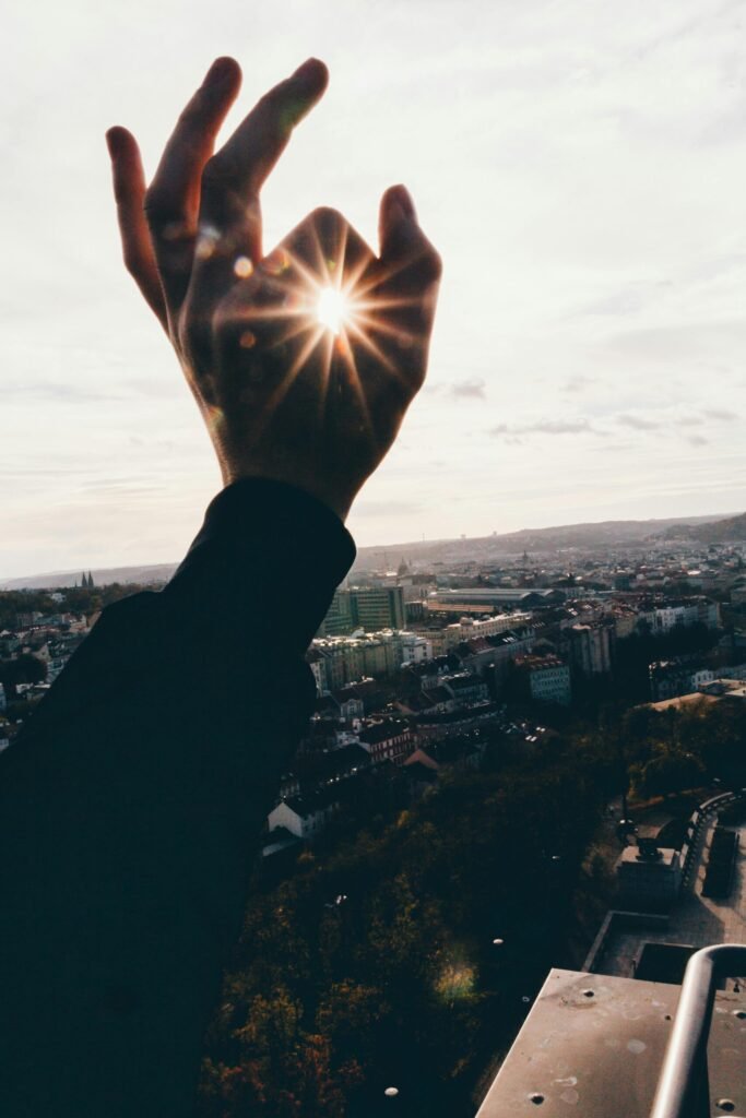 Hand reaching towards sunbeam over cityscape, creating a scenic and dramatic urban view.
